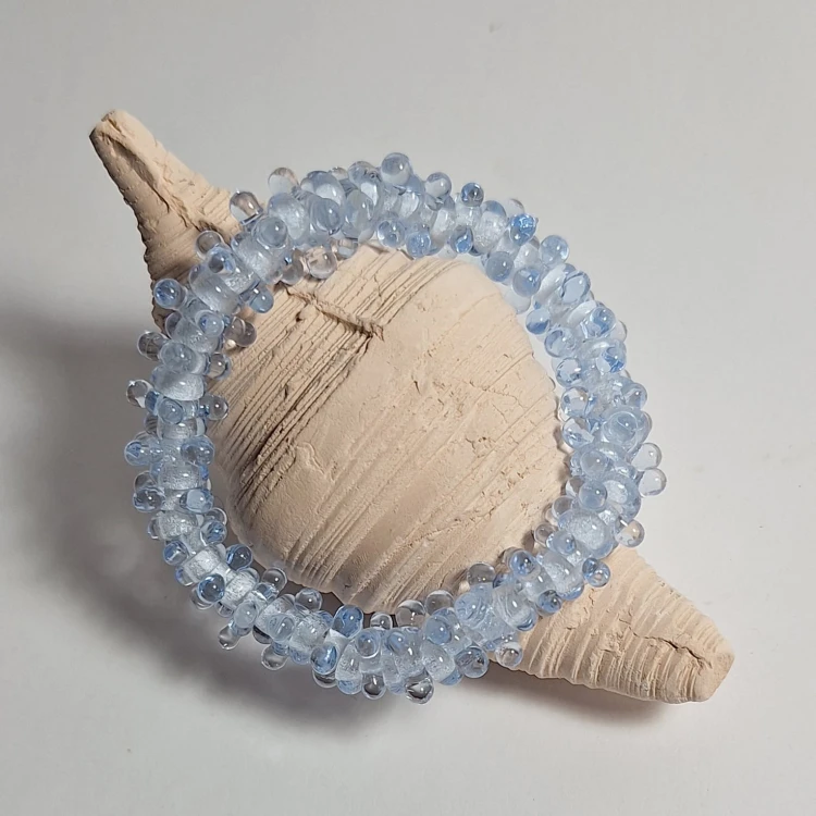 Kraina Lodu  ręcznie wykonana bransoletka  ze szkła artystycznego  lampwork prezentowana oparta o kamień
