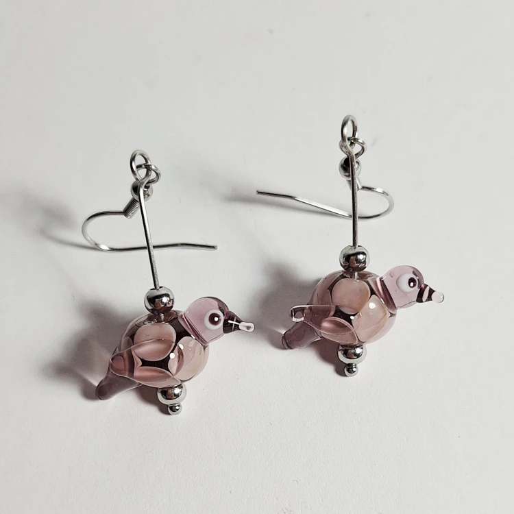 Lawendowy Śpiew ręcznie wykonane dwa kolczyki ze szkła artystycznego  lampwork  lezące na stole
